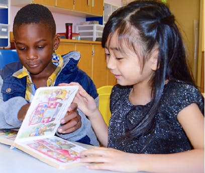 Two children looking at an open book together