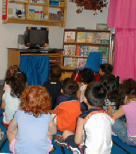 Children sitting on the floor watching a television
