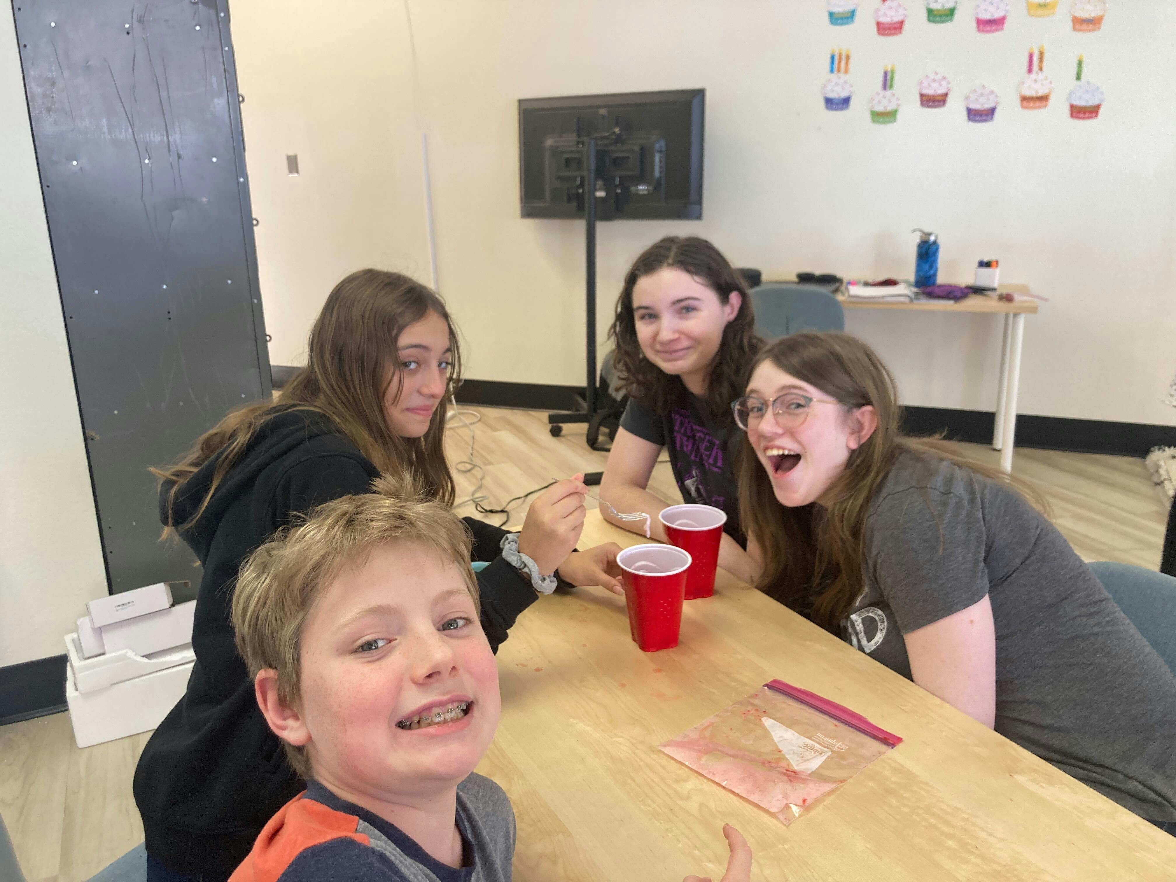 Four people sitting around a table with red cups