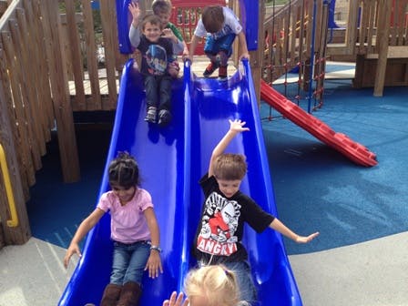 Children playing on blue slides at a playground