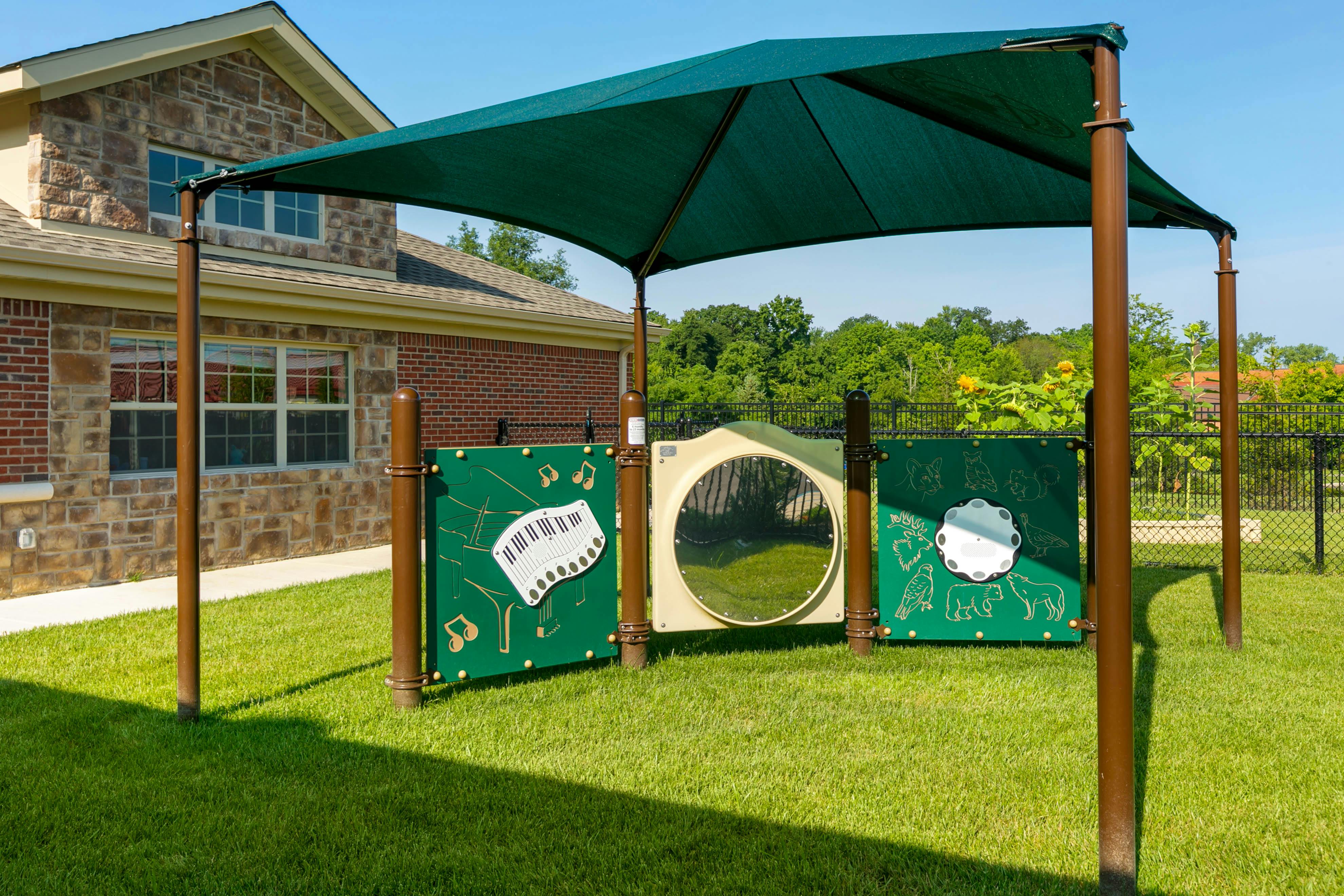 Playground musical panels and mirror under a green shade structure