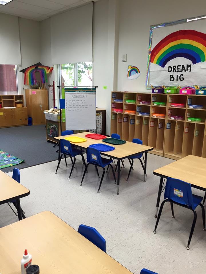 Classroom with small tables and chairs, storage cubbies, and a whiteboard