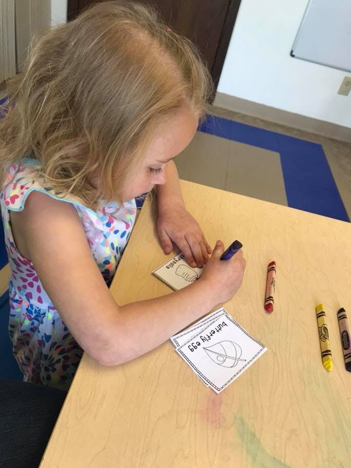 Child writing on a small card at a table