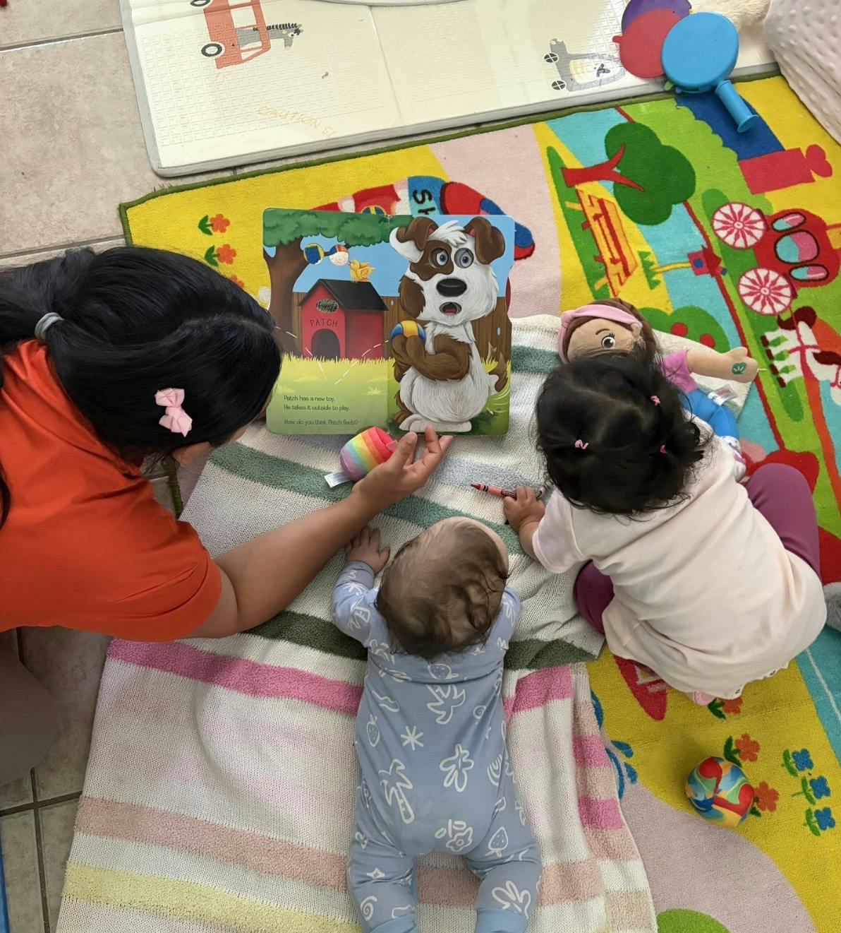 Person reading a children's book to a child and an infant