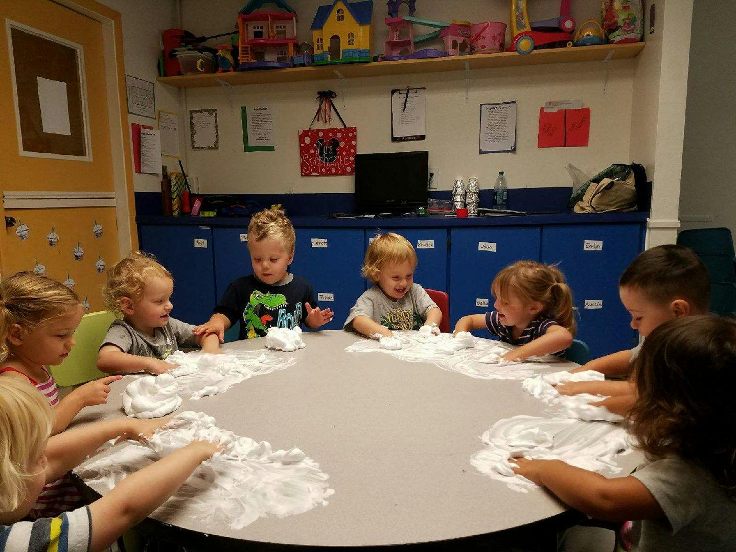 Children playing with white foam at a table
