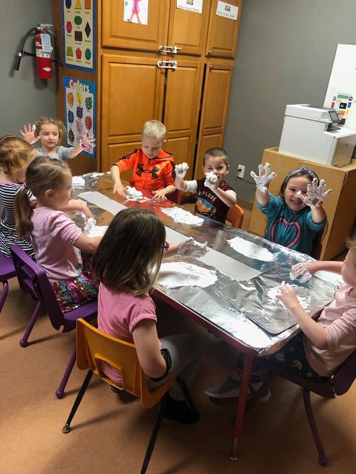 Children playing with white foam at a table