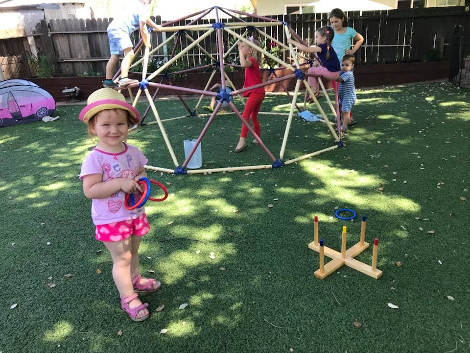 Child in a hat holding rings, other children playing on a jungle gym