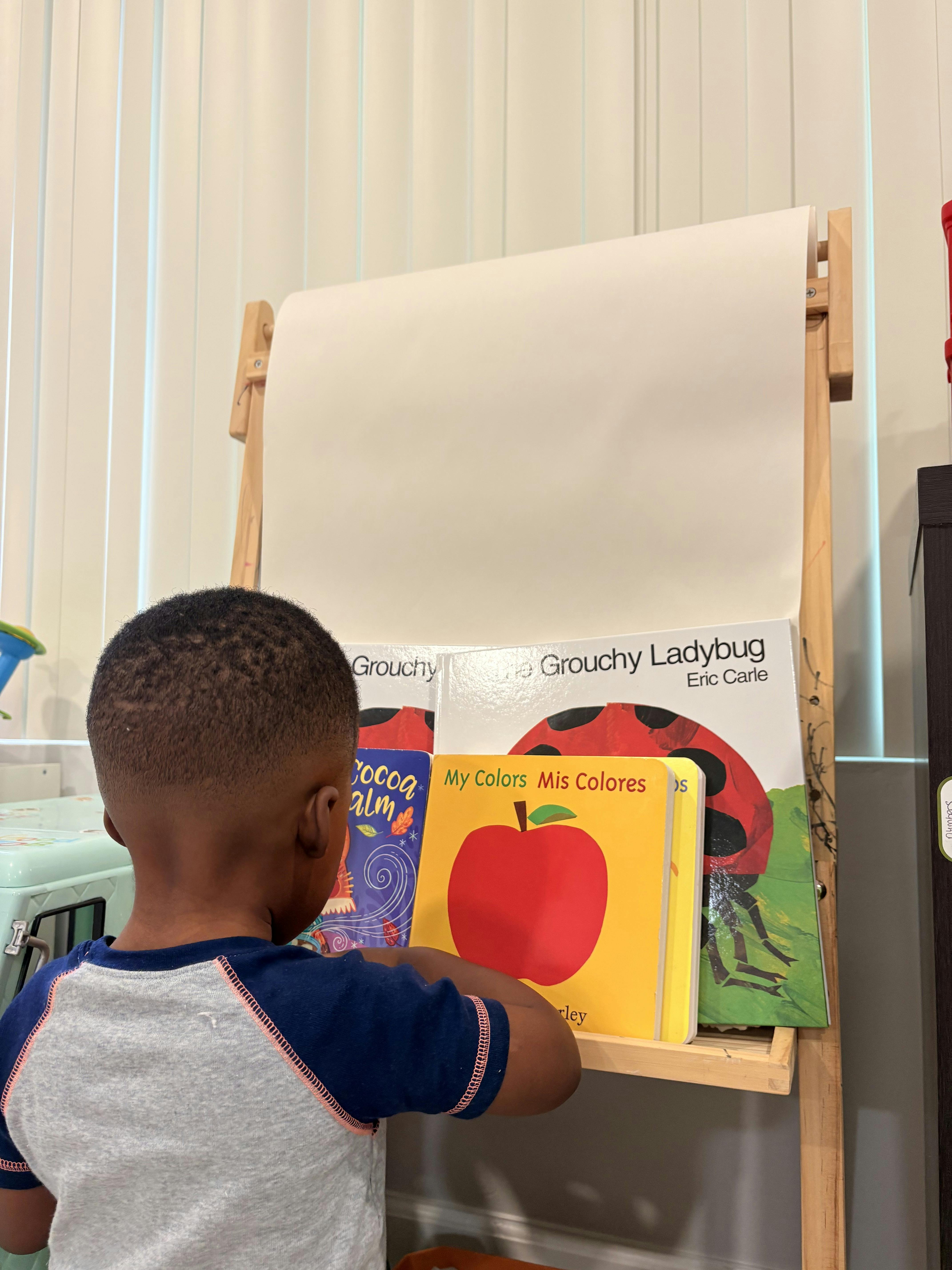 Child looking at picture books on a display easel