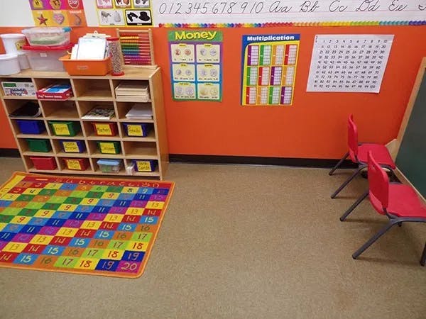 Classroom with colorful rug, storage unit, and educational posters
