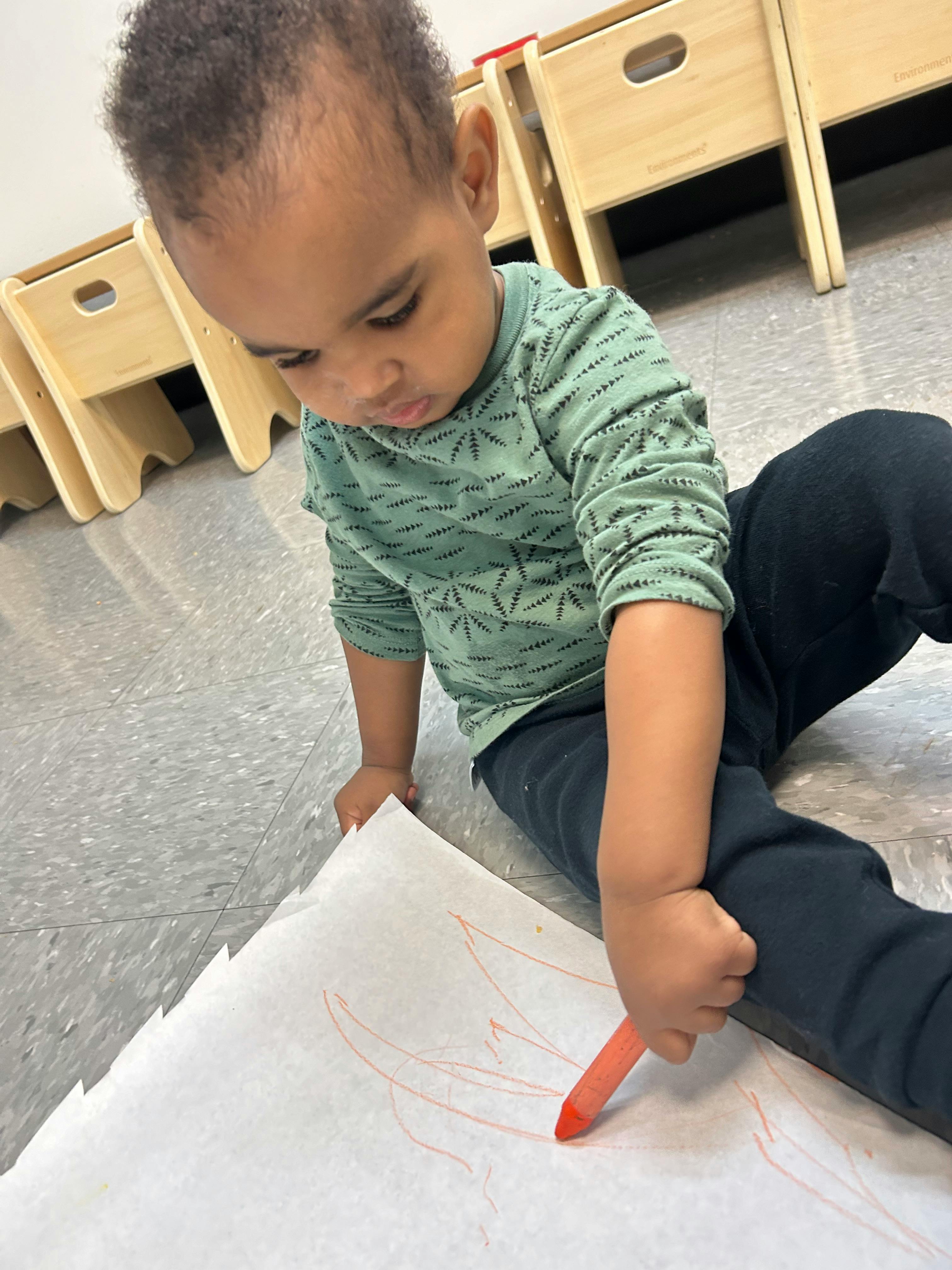 Child drawing on paper with a crayon