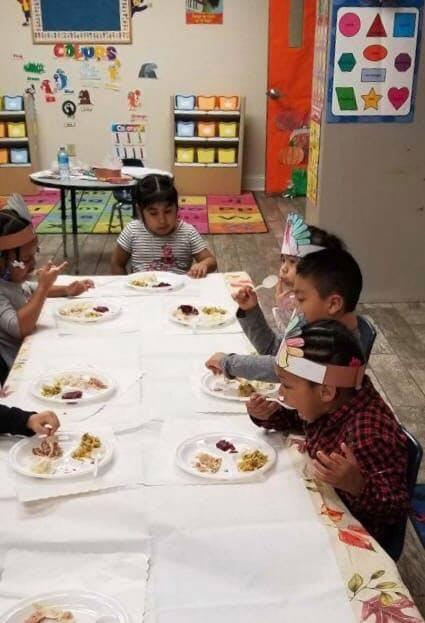 Children eating at a long table in a classroom