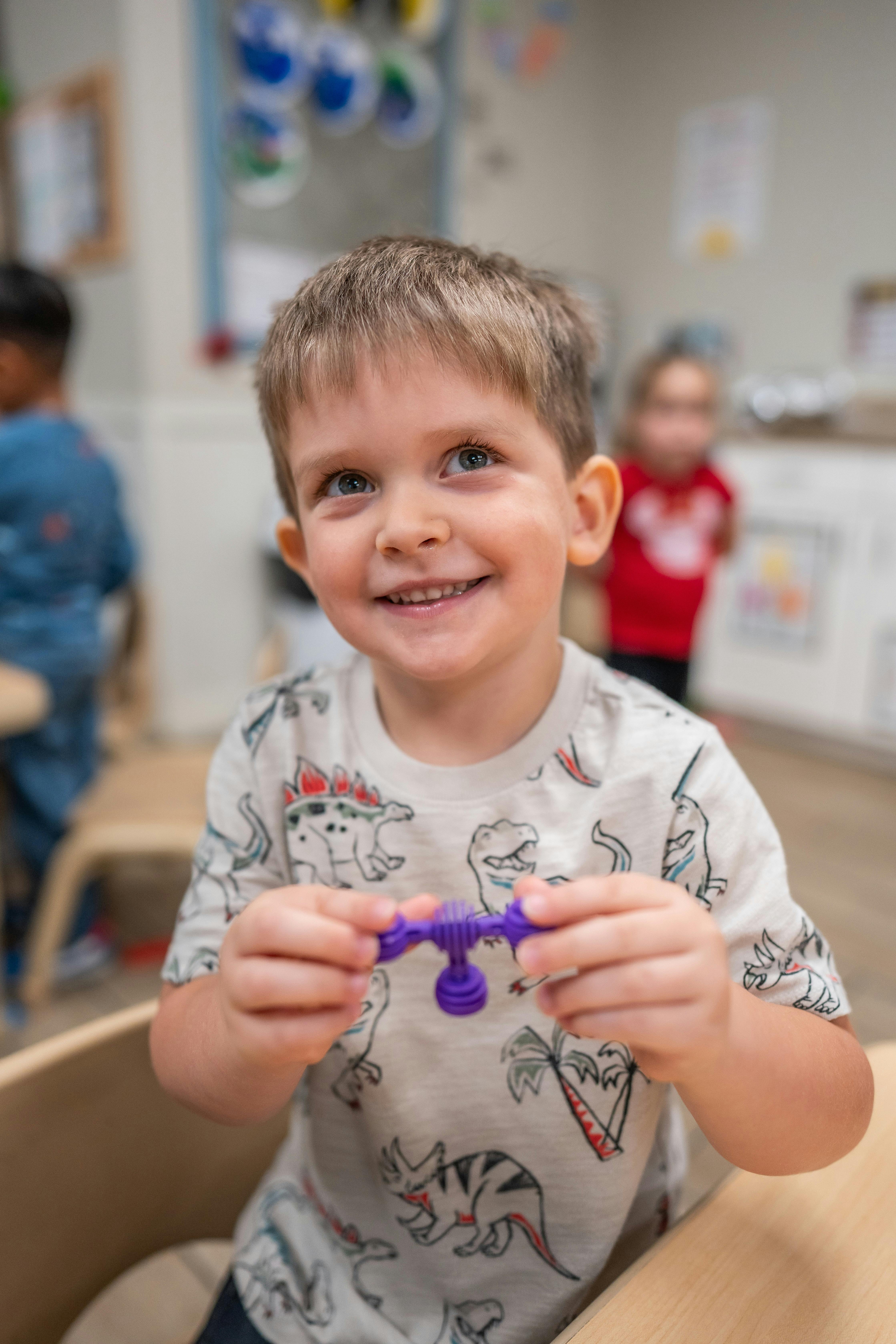 Child playing with a small plastic toy in a classroom