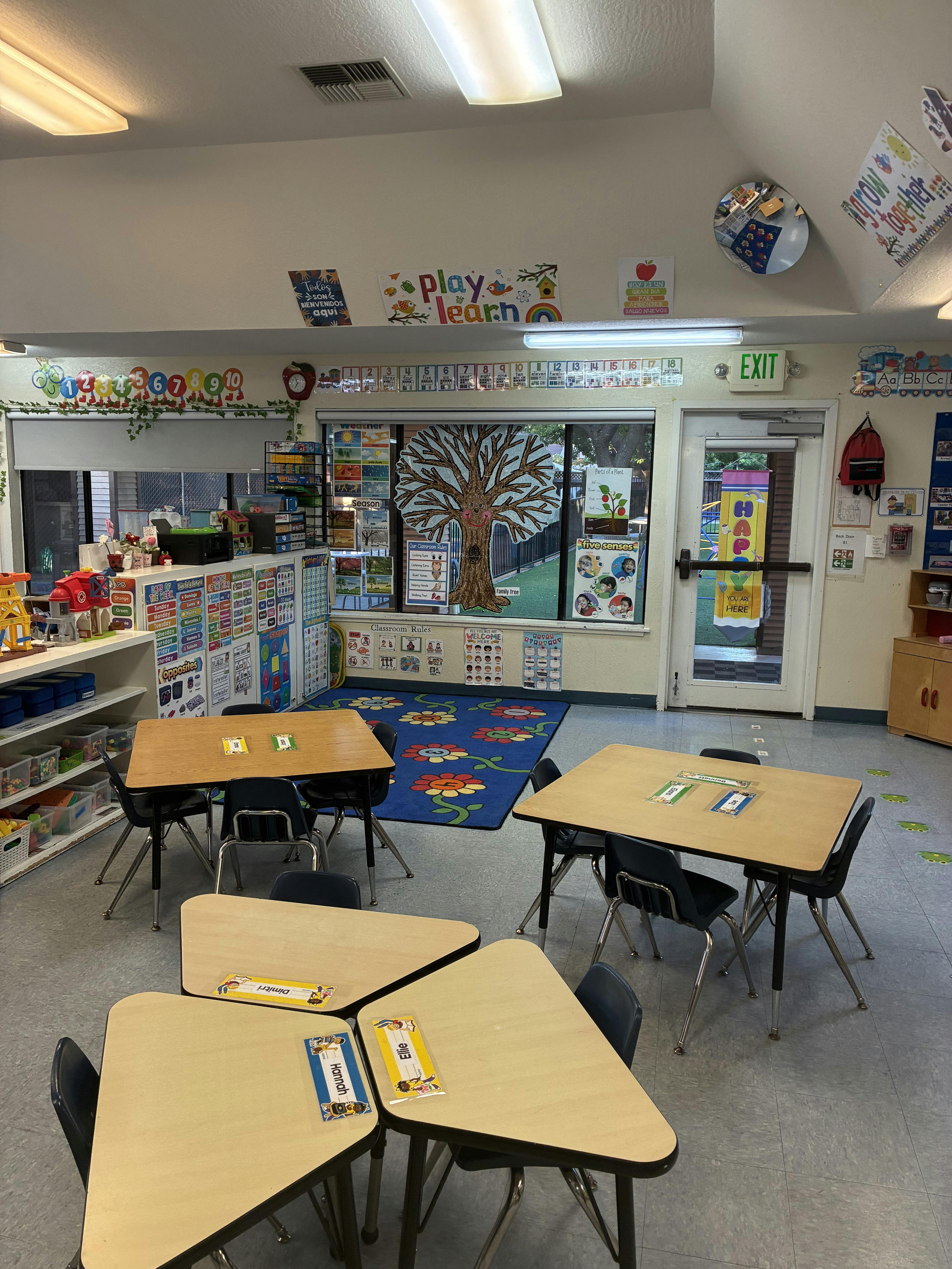 Empty preschool classroom with tables and educational wall decorations