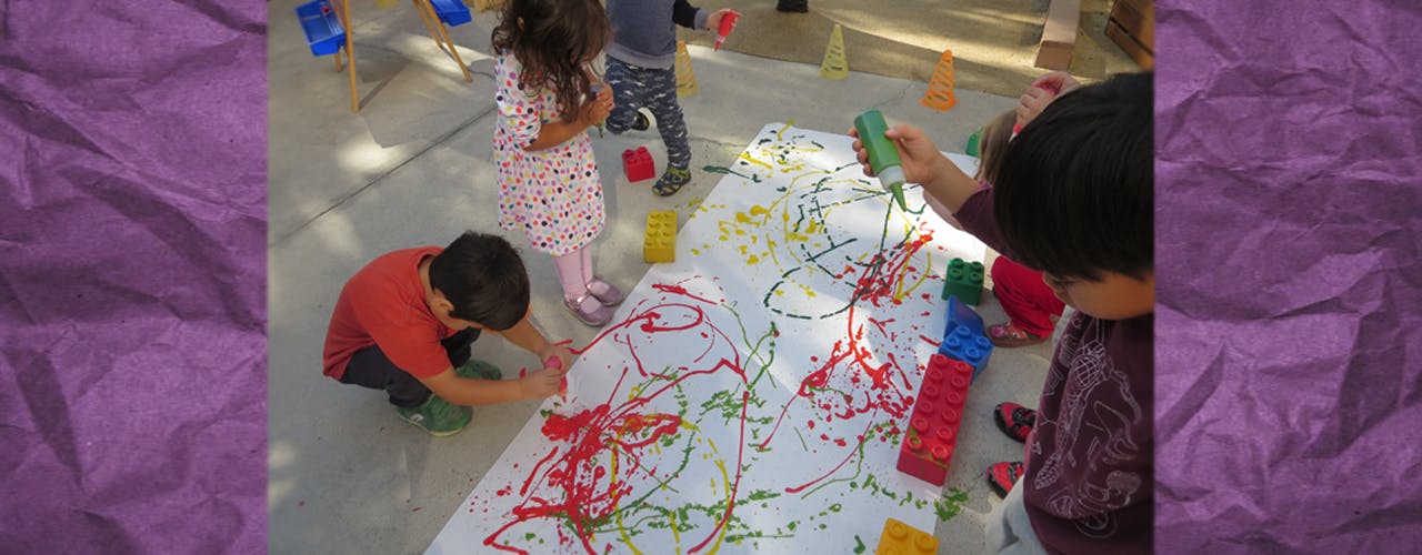 Children painting on a large white sheet