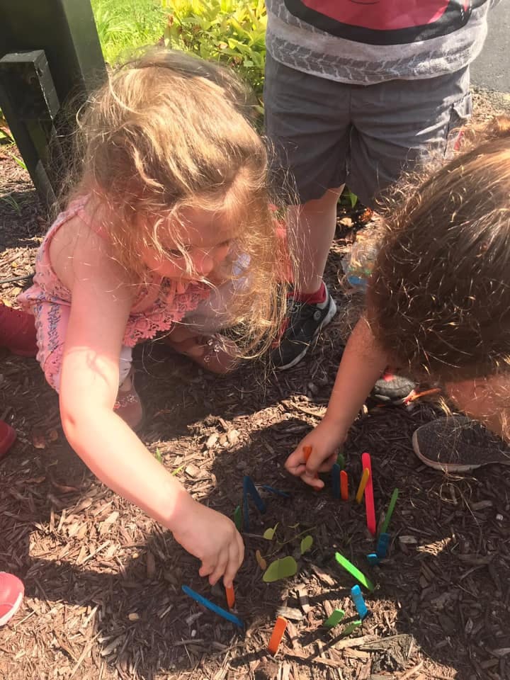 Child playing with colorful sticks in the dirt