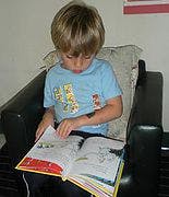 Child sitting in a chair and reading a book