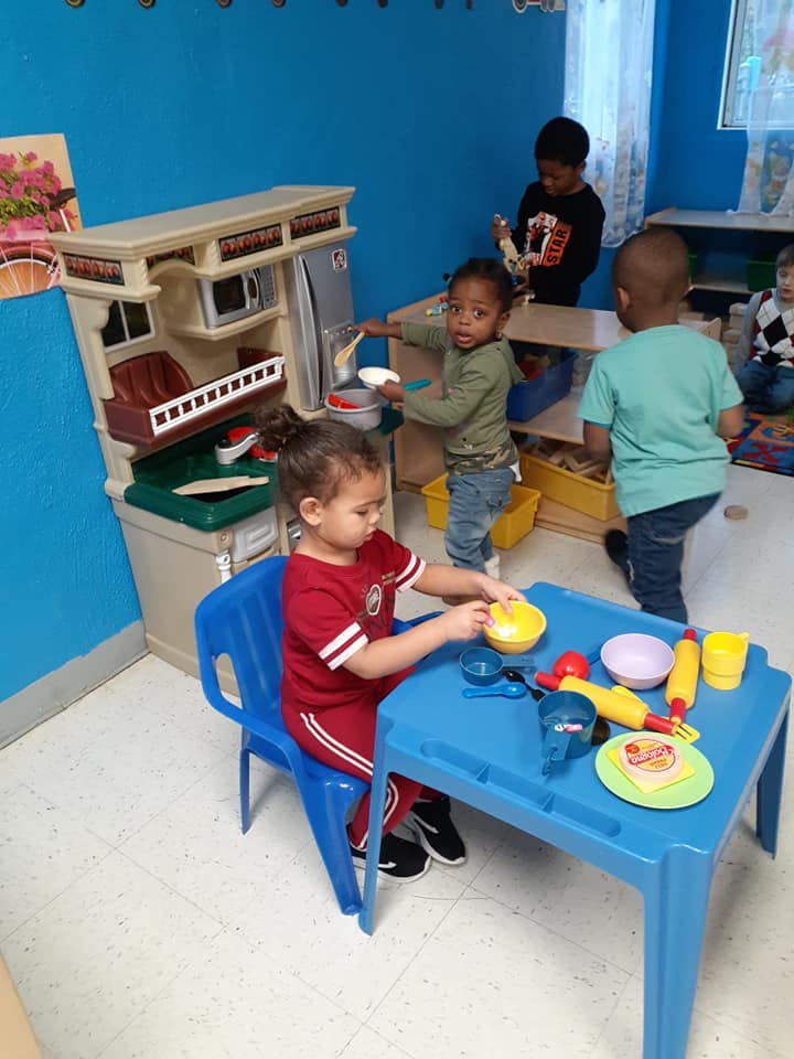 Children playing with toy kitchen and play food at a table