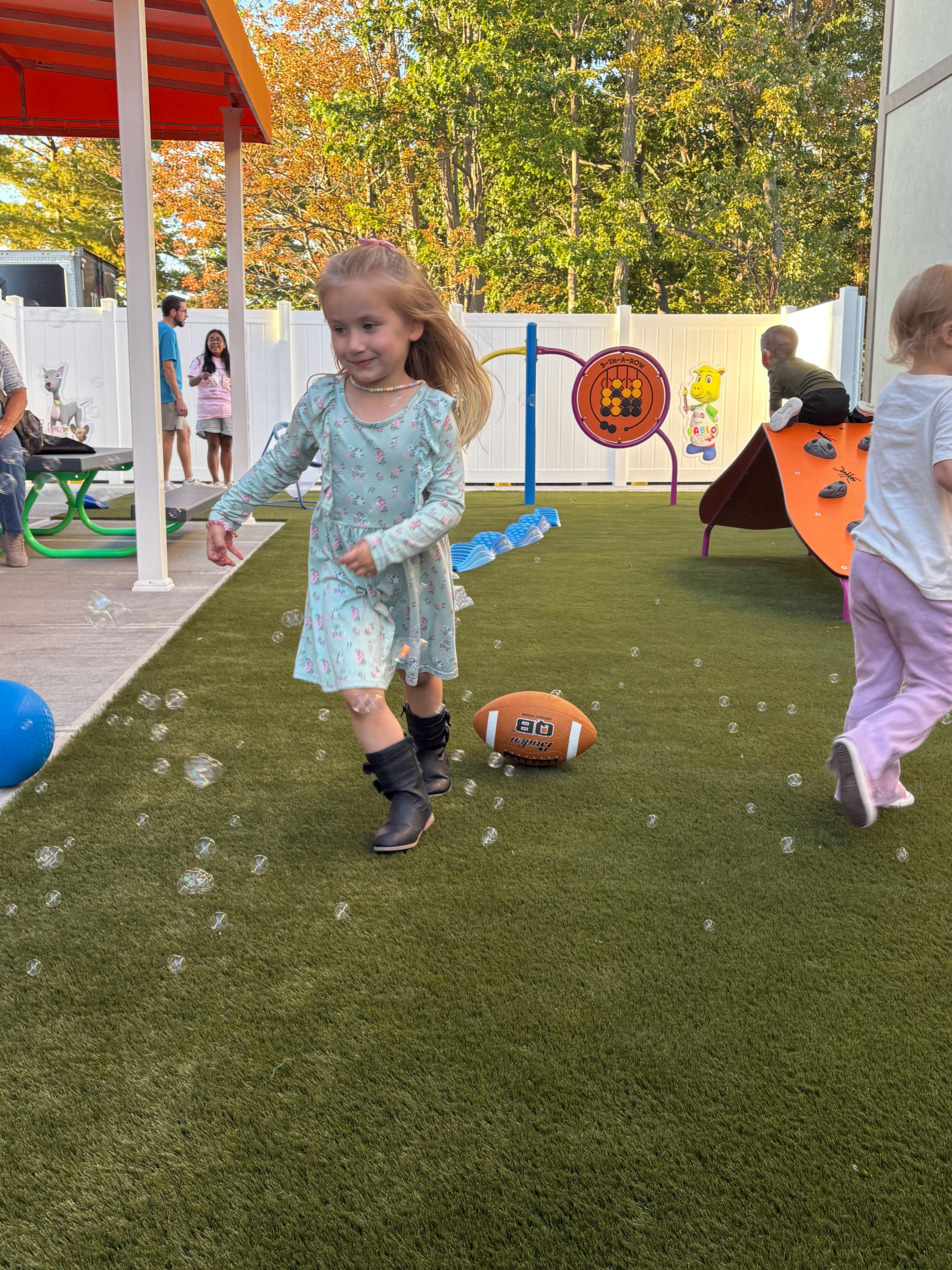 Child playing among bubbles on artificial grass