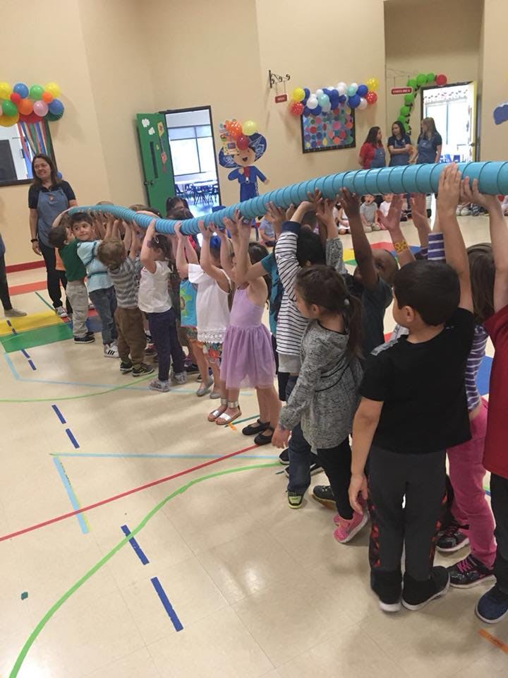 Children holding a long blue tube above their heads in a line