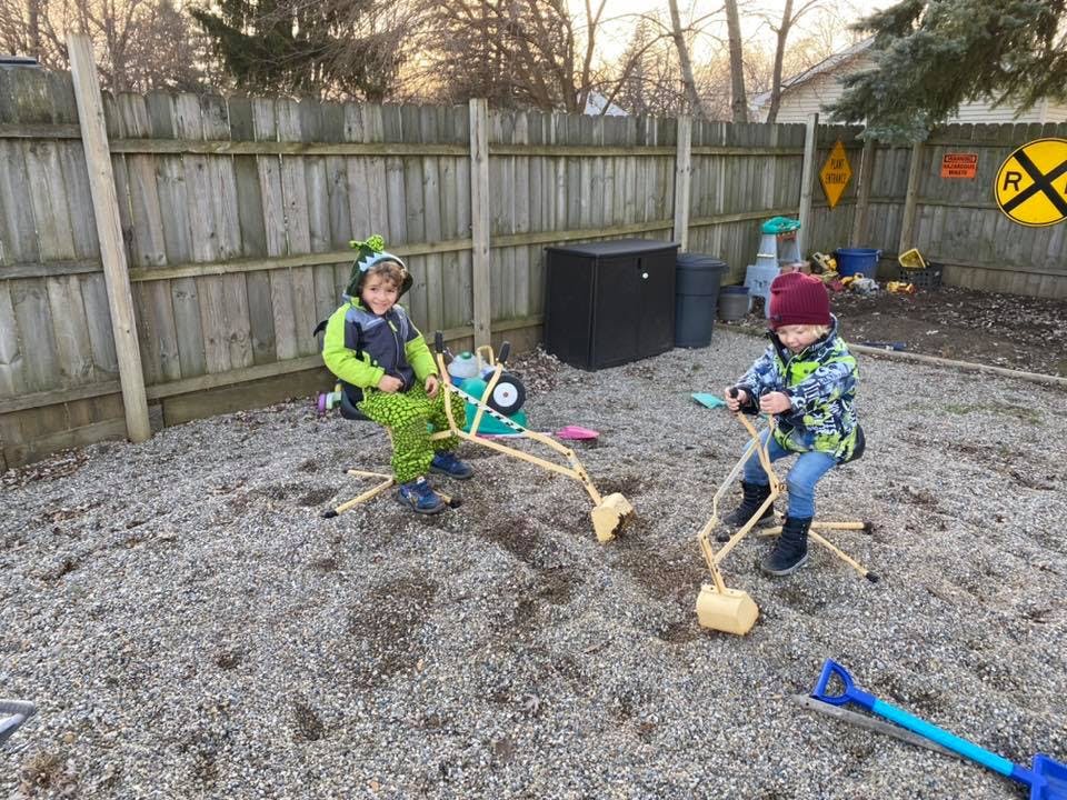 Two children playing with digger toys in a gravel area
