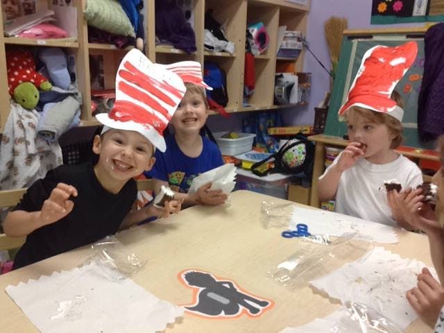 Children wearing red and white striped hats at a table