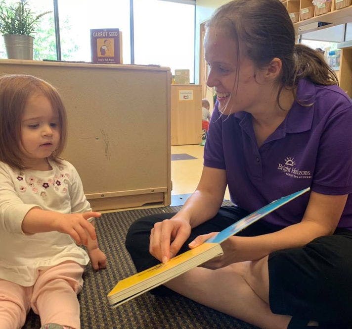 Adult and child sitting on floor reading a book