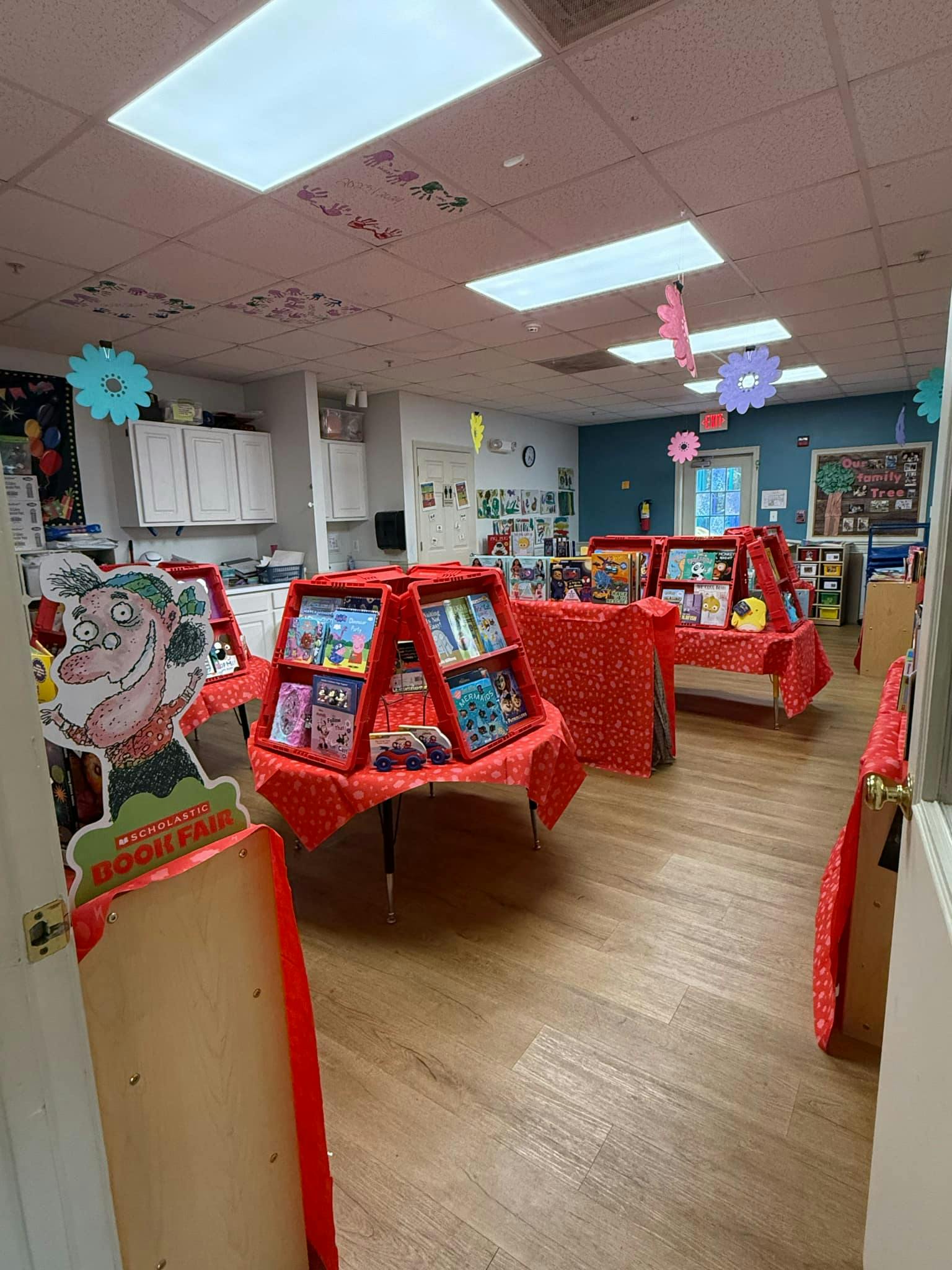 Scholastic Book Fair display in a room with books on red-covered tables
