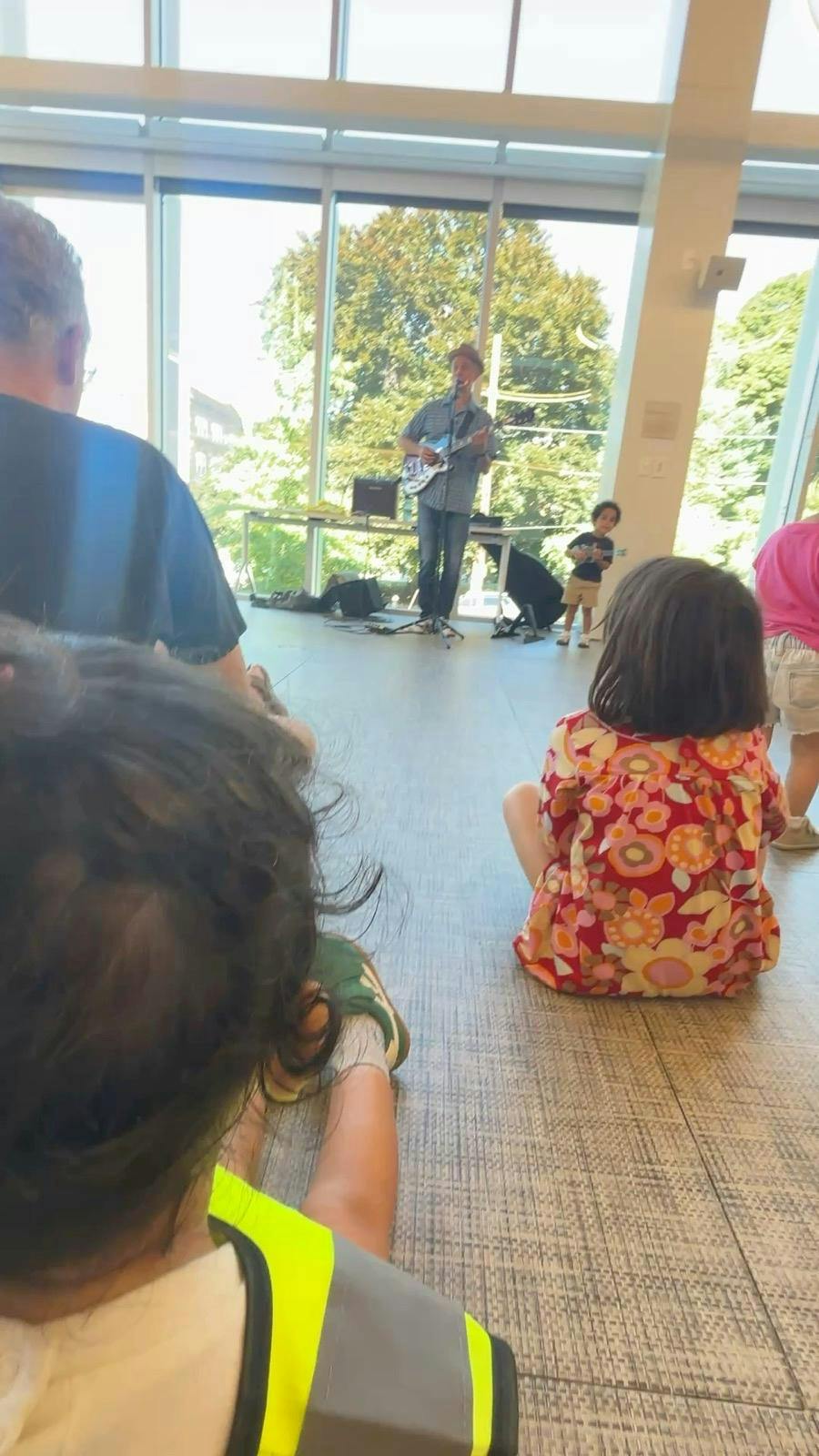 People watching a musician play guitar in a bright room