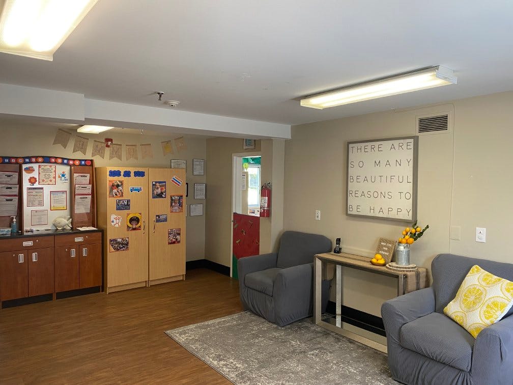 Lobby area with chairs, cabinets, a rug, and a sign that says, "There are so many beautiful reasons to be happy"