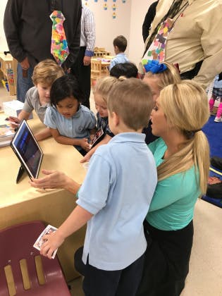 Adult and children gathered around a tablet