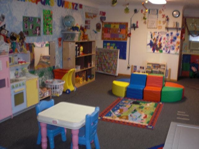 Playroom with small table and chairs, colorful seating, and toys