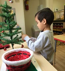 Child decorating a small Christmas tree