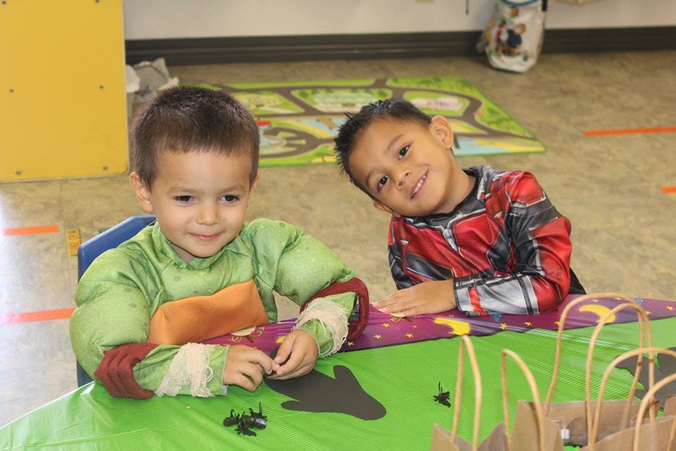 Two children in costumes sitting at a table