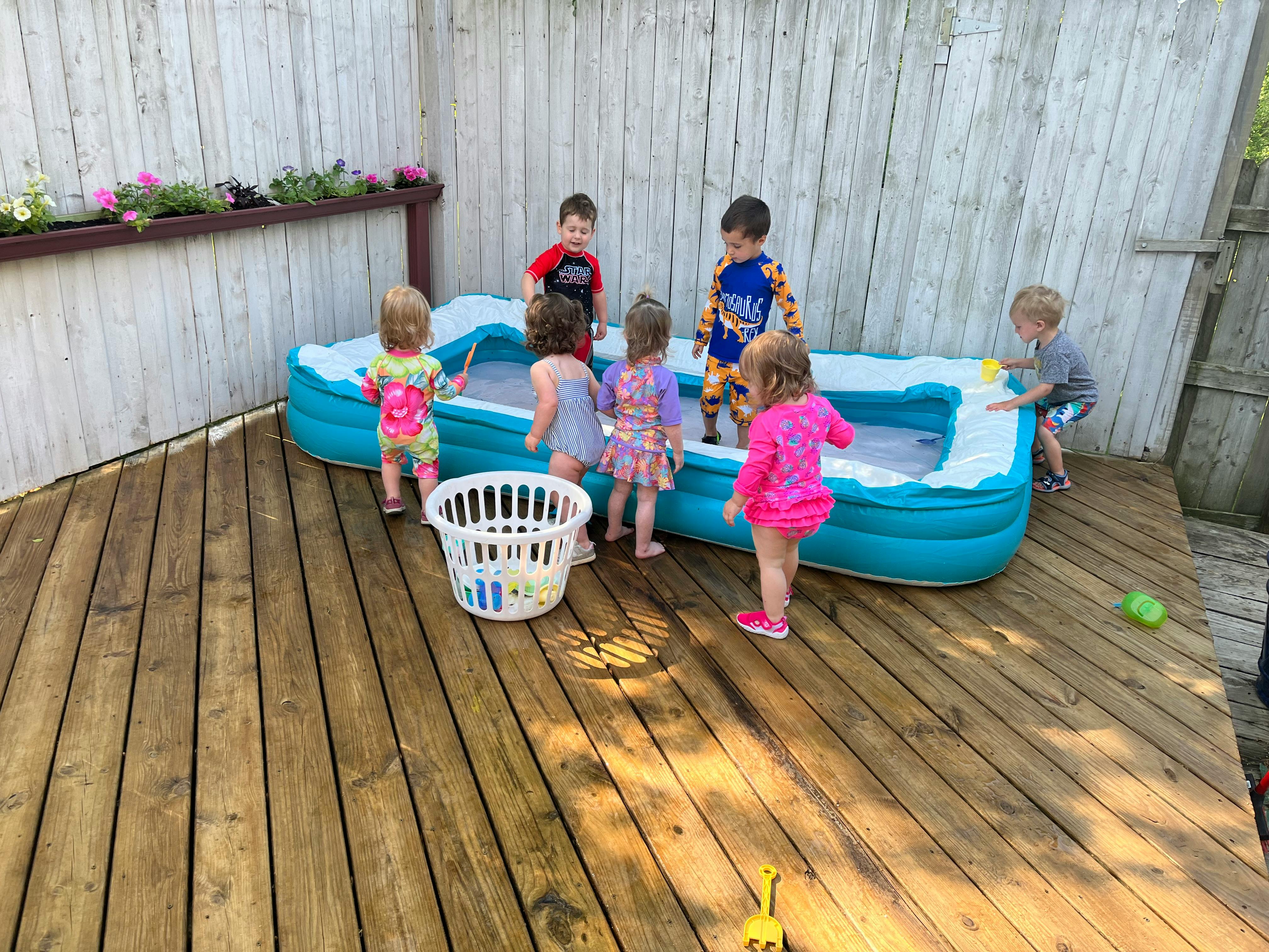 Children playing in an inflatable pool on a wooden deck
