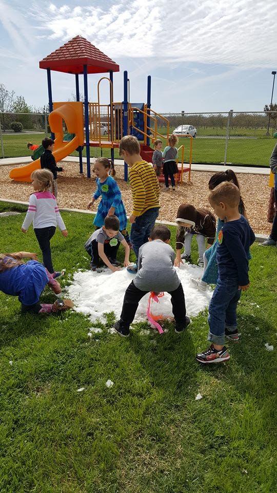 Children playing with a pile of white material on a grassy playground