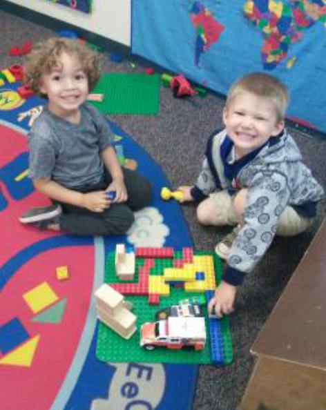 Two children playing with building blocks on a colorful rug