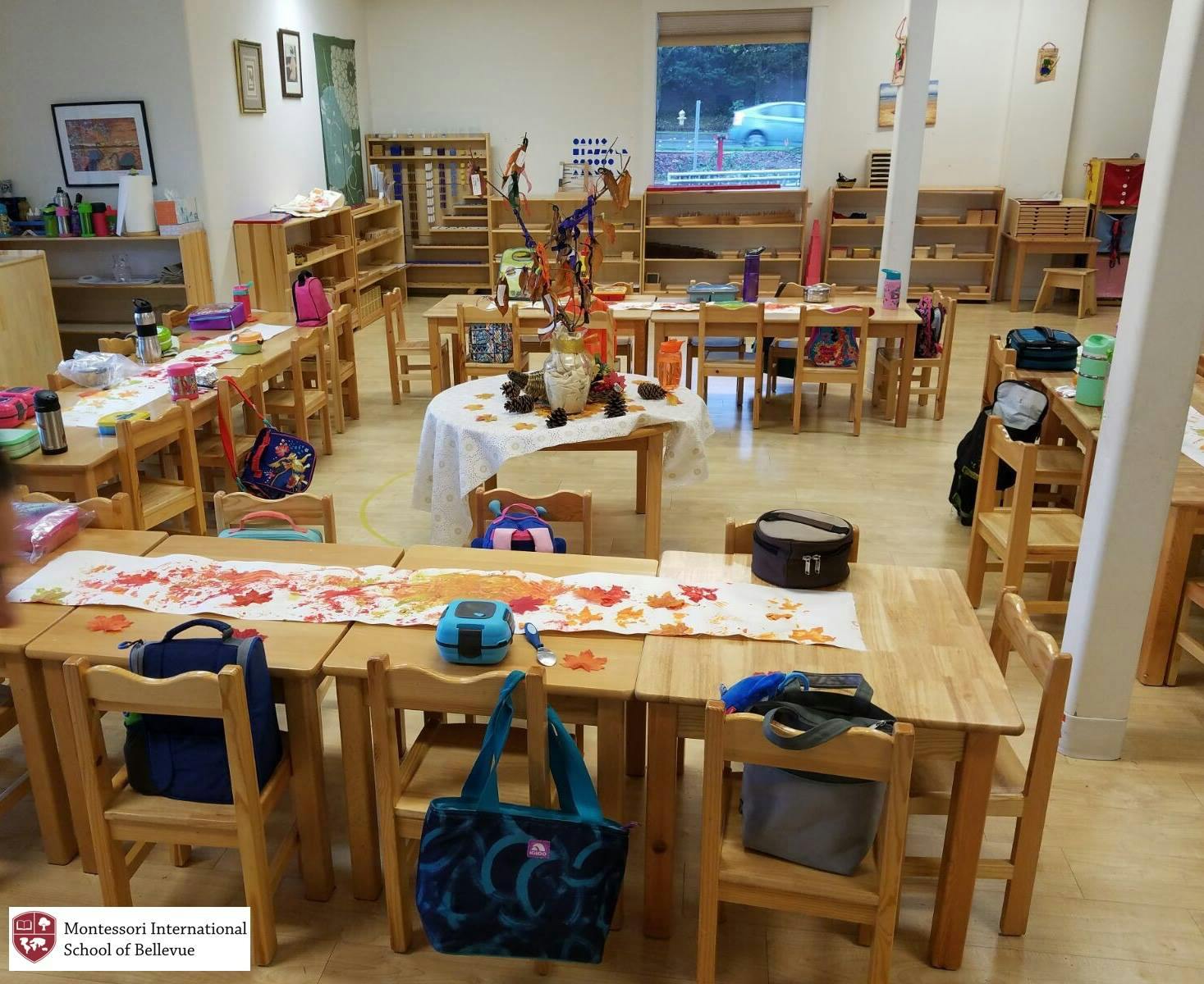 Classroom with small wooden tables and chairs, some decorated with fall leaves