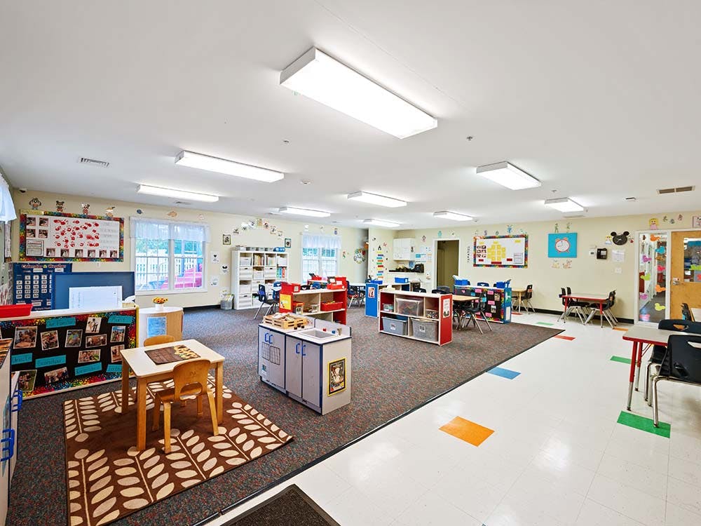 Empty classroom with small tables, chairs, and learning materials