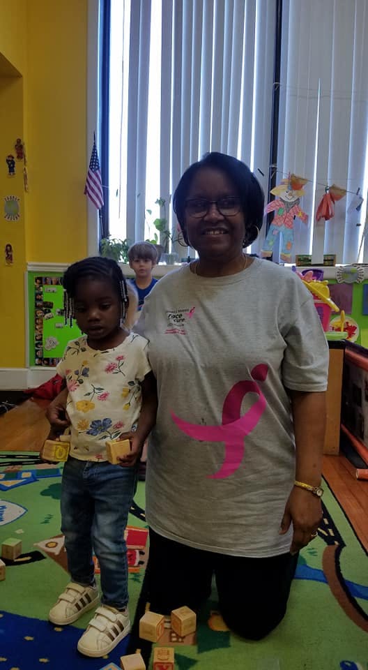 Adult and child standing in a classroom with building blocks