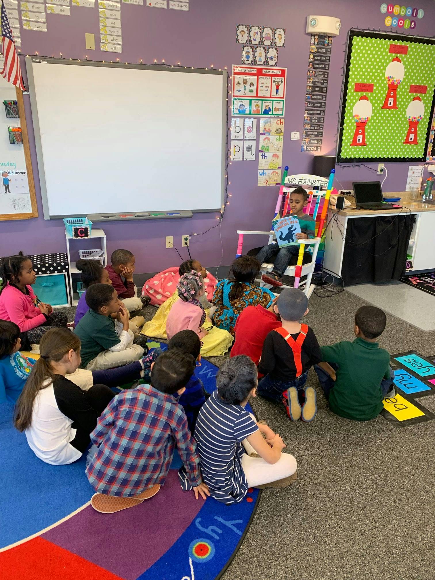 Child reading to a group of children sitting on the floor in a classroom
