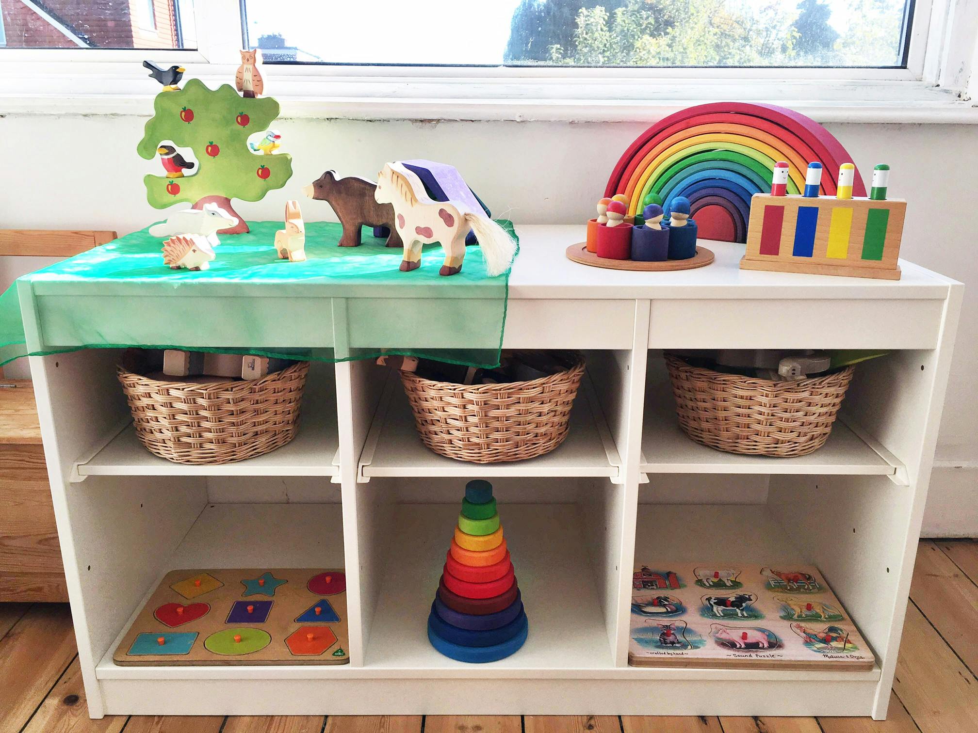 White shelving unit with baskets, puzzles, and colorful toys