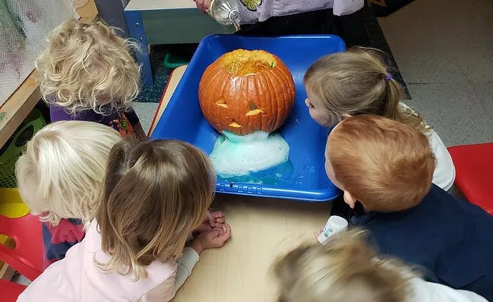 Children watching a carved pumpkin erupting with foam