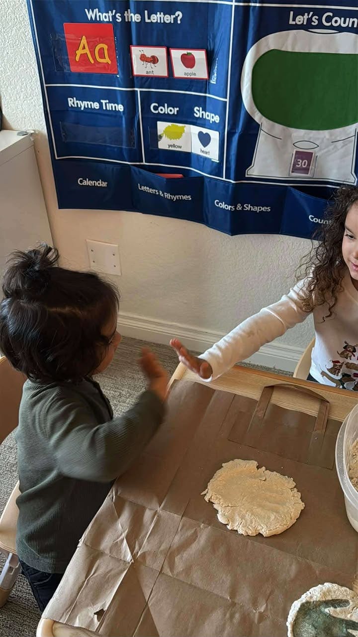 Two children playing with dough at a table