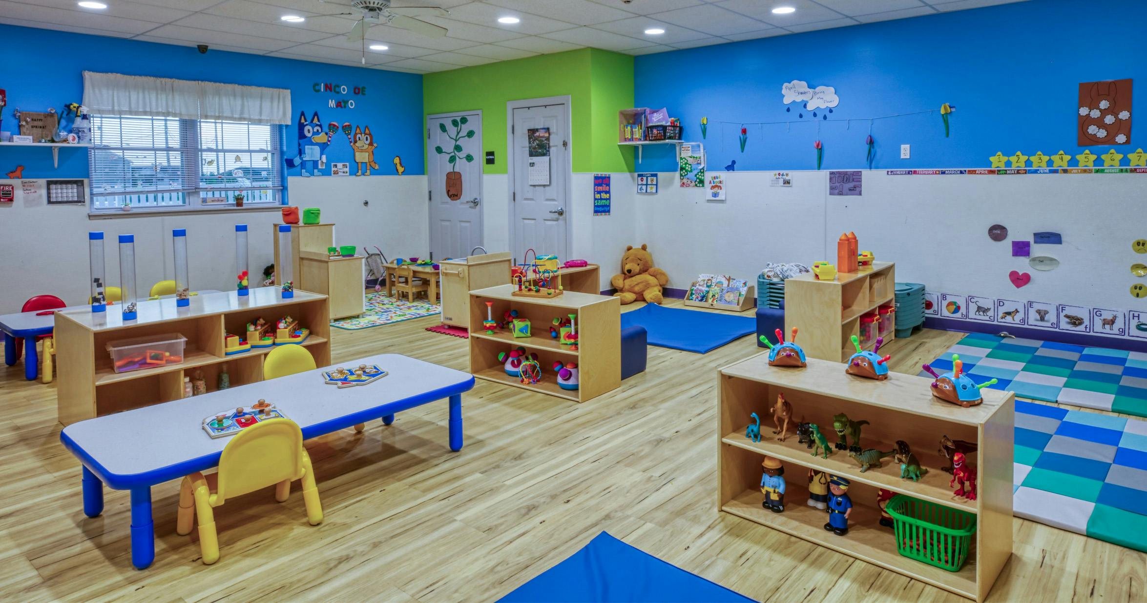 A colorful classroom with tables, chairs, and shelves filled with toys