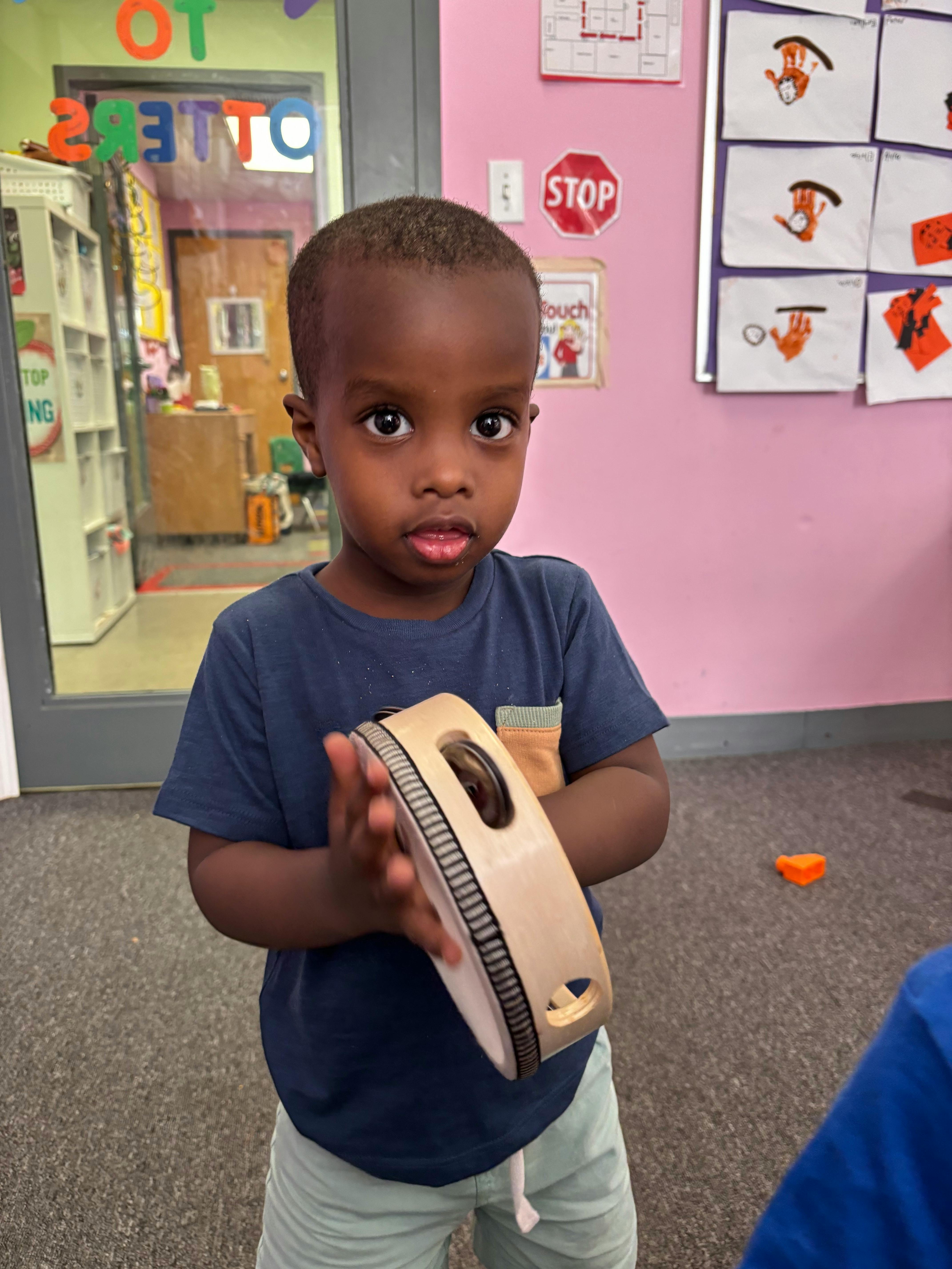 Child holding a tambourine in a classroom