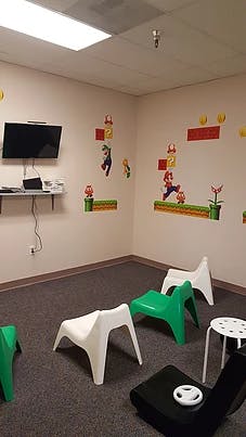 Room with Mario-themed wall decals, a TV, and small chairs