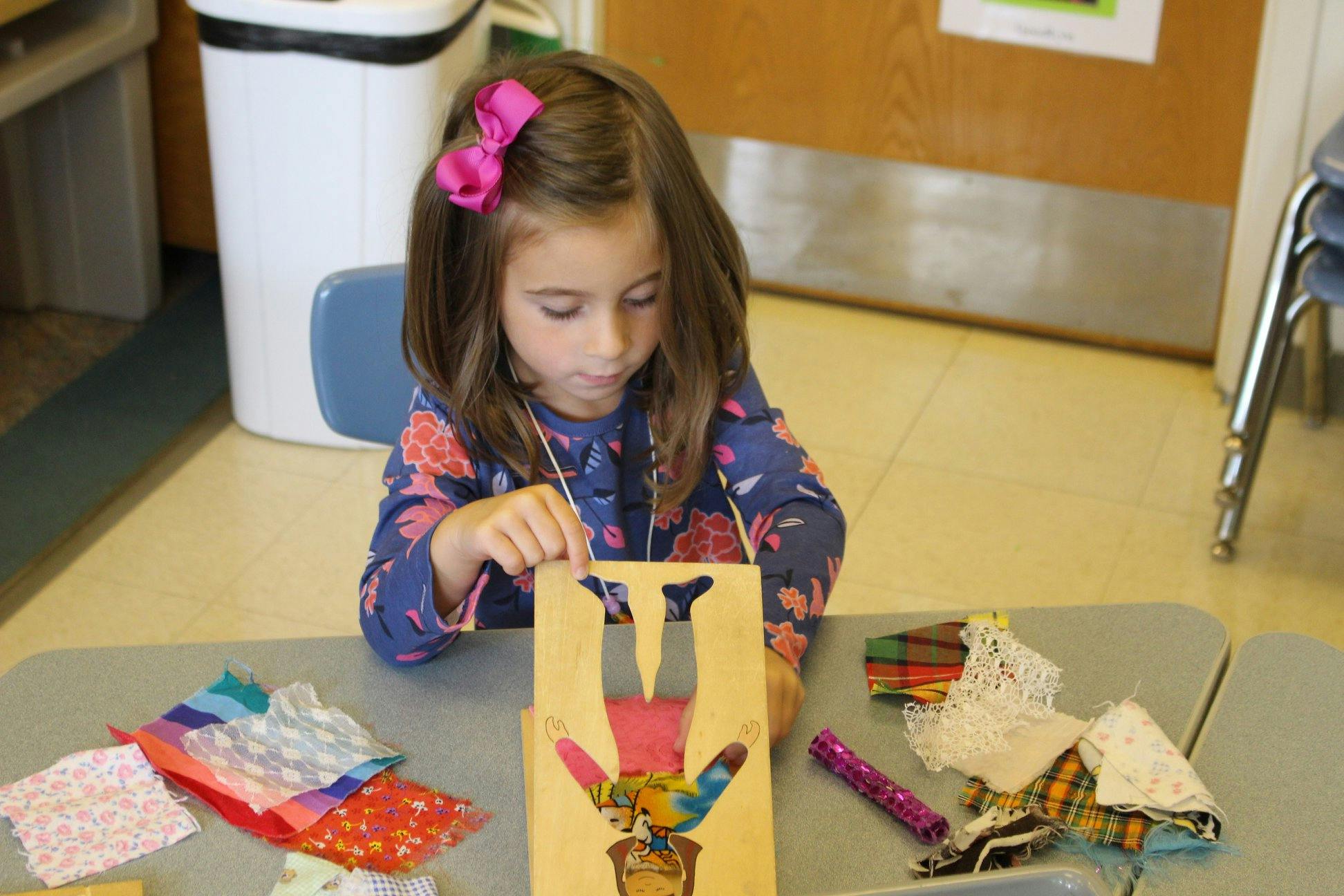 Child creating art with paper cutouts at a table