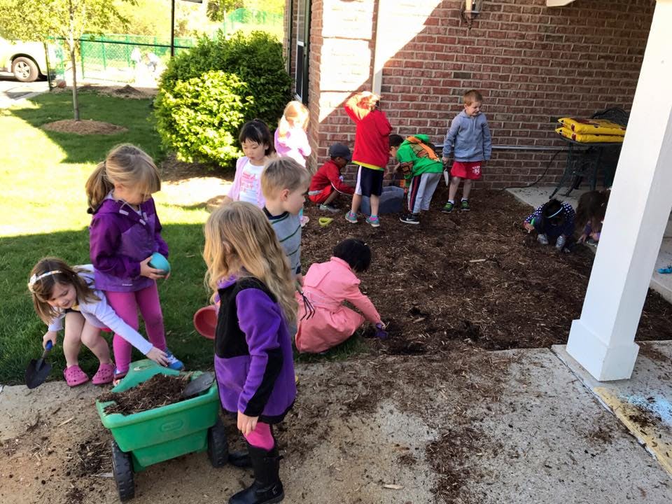 Children playing in dirt with a wheelbarrow