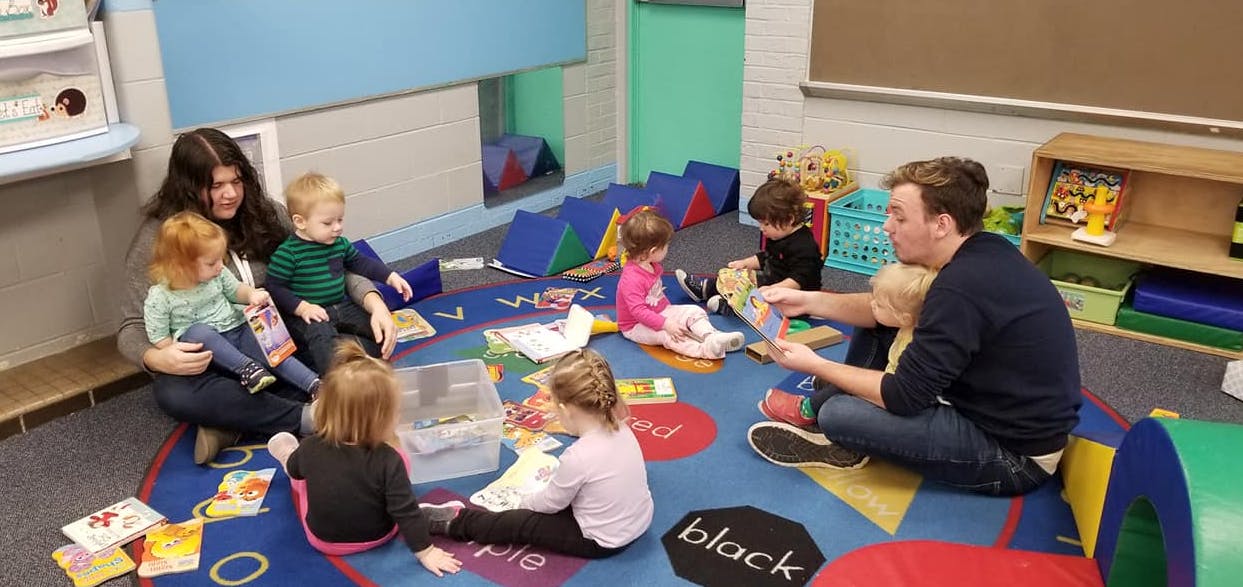 Two adults reading to children in a classroom
