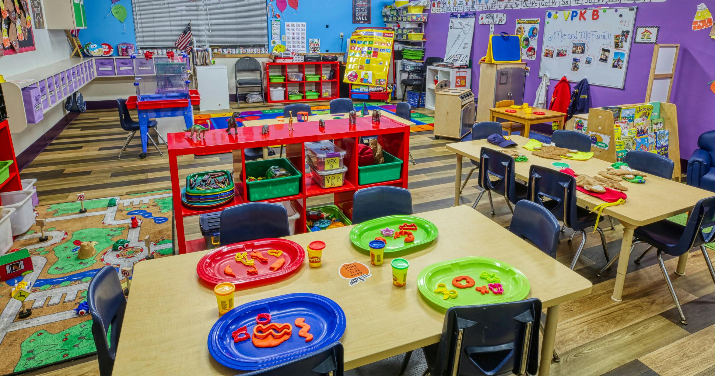 Classroom with tables set up for activities, colorful rugs, and learning materials
